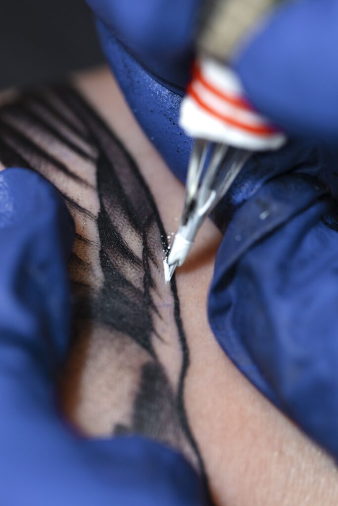 tatouage en cours de réalisation par un tatoueur à l'ancre blanche